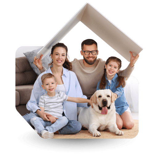 The image shows a cheerful family of four—with two adults and two children—sitting together on the floor. They are smiling and posing with a friendly Labrador dog in front of them. The adults are holding a roof-shaped object above their heads, giving the impression of being under a house roof. The setting looks homey and warm, with a sofa and soft tones in the background, creating a cozy, family-oriented scene.