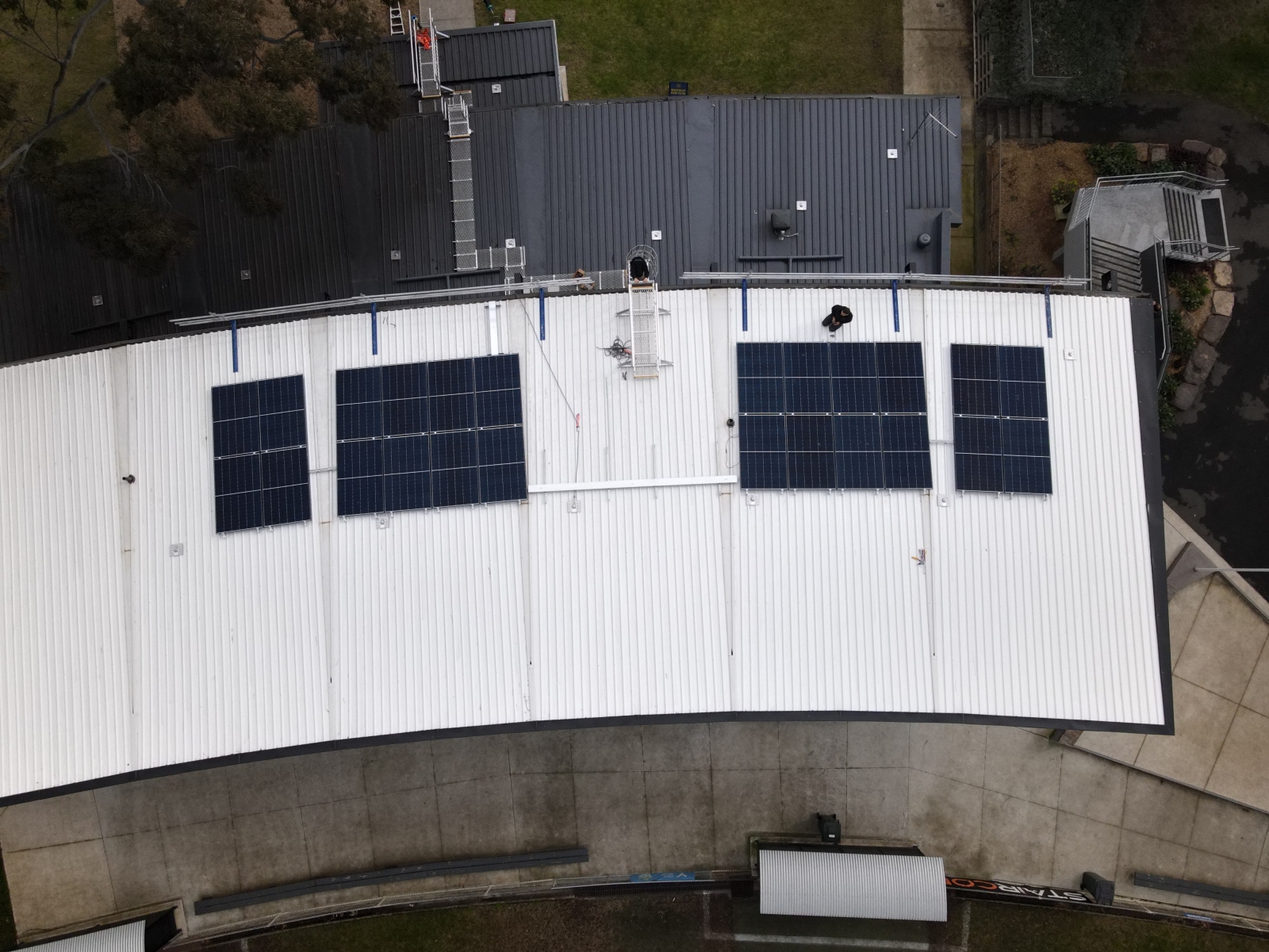 Aerial view of a solar array installed across the curved metal roof of a commercial building